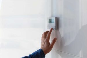 A person examining the air filter of a home air conditioning system indoors.