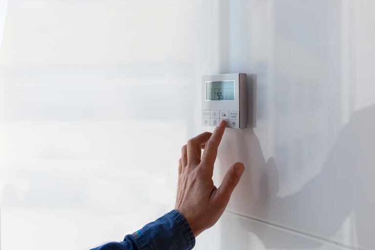 A person examining the air filter of a home air conditioning system indoors.